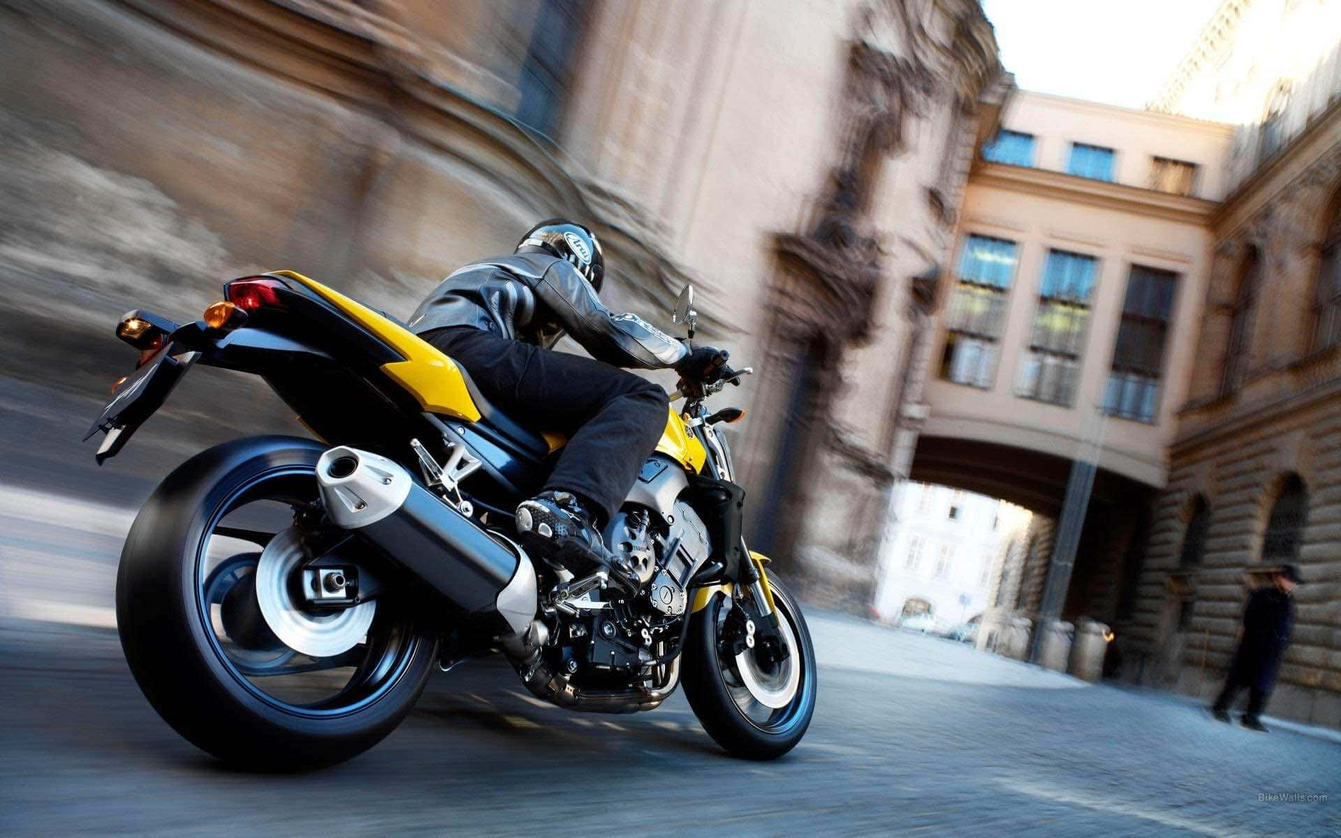 Et billede af en person på motorcykel, der suser gennem byen.