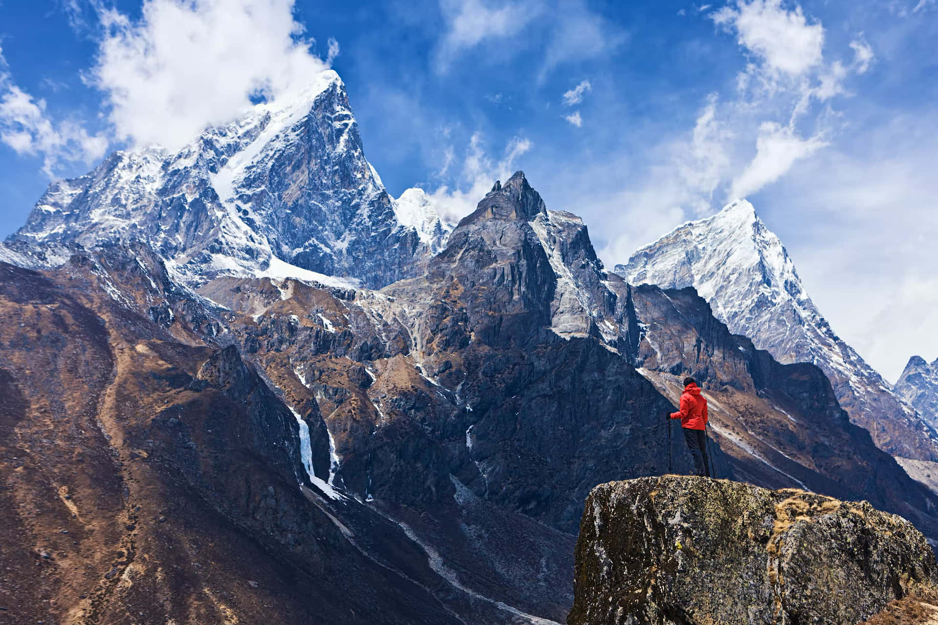 A Man Standing On Top Of A Mountain With Mountains In The Background