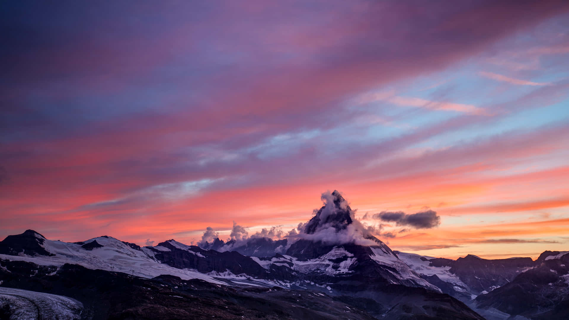 En bjergkæde med et farverigt himmeltegn ved solnedgang Wallpaper