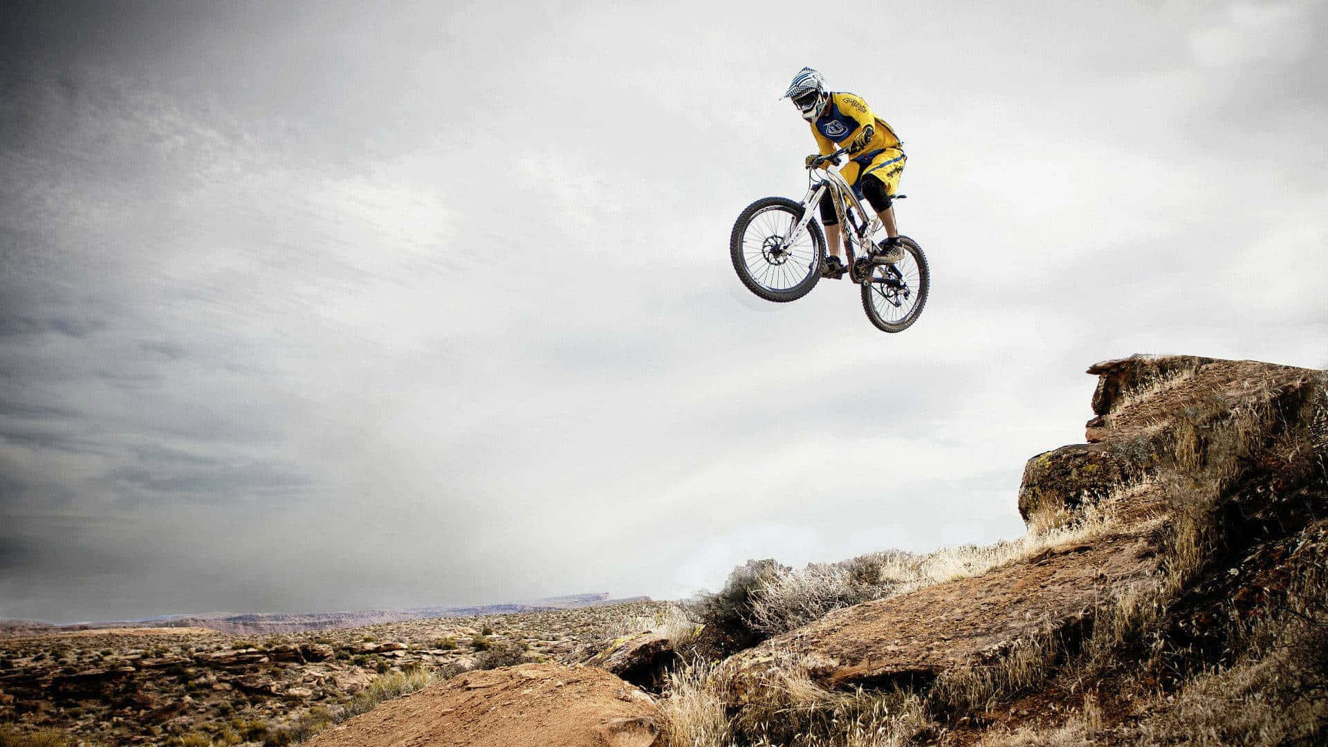 Mountain Biker Mid Air Jump_ Desert Landscape Wallpaper