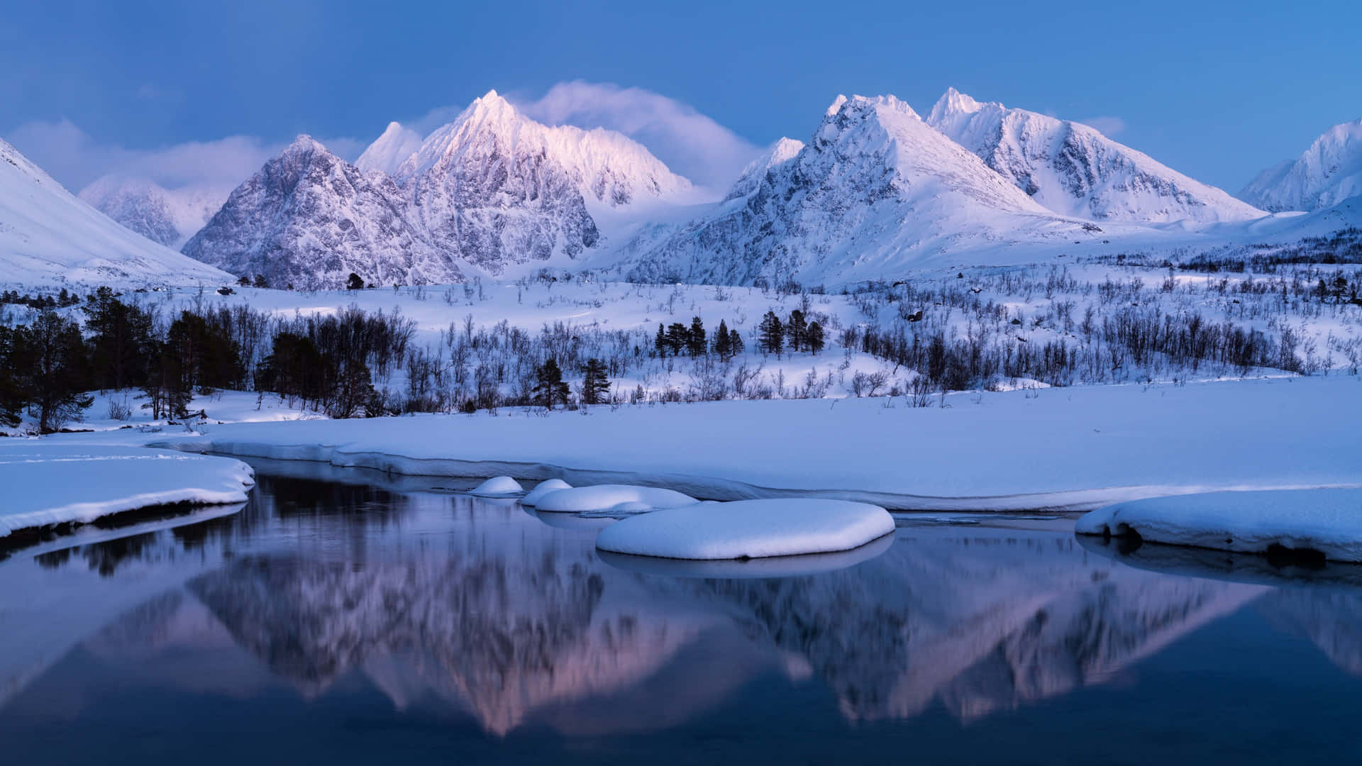 Et snebelagt bjergkæde spejles i en flod