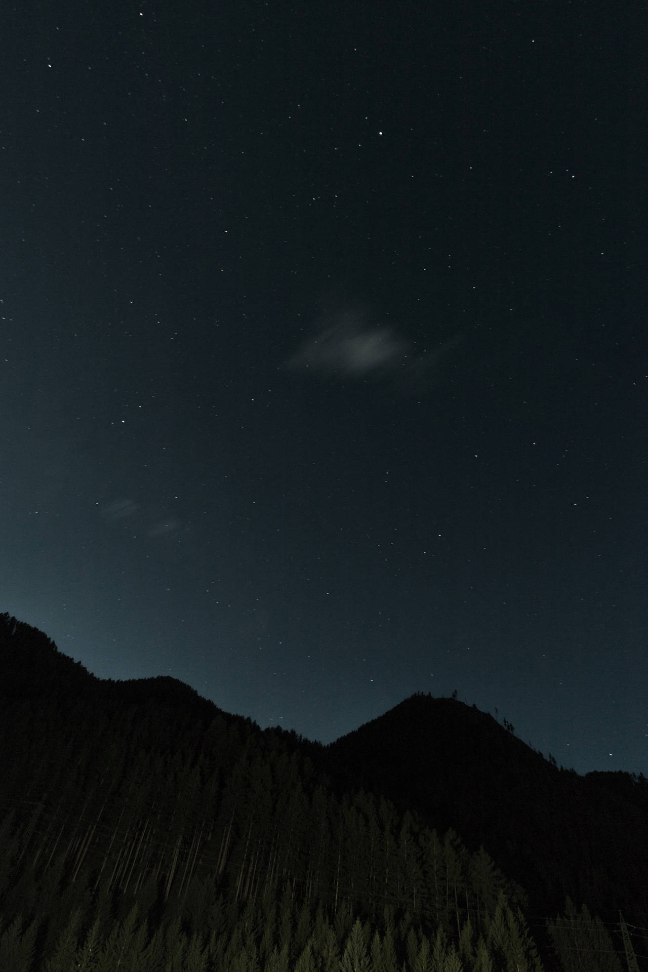A dimly lit, star-filled sky above a stunning mountain silhouette. Wallpaper