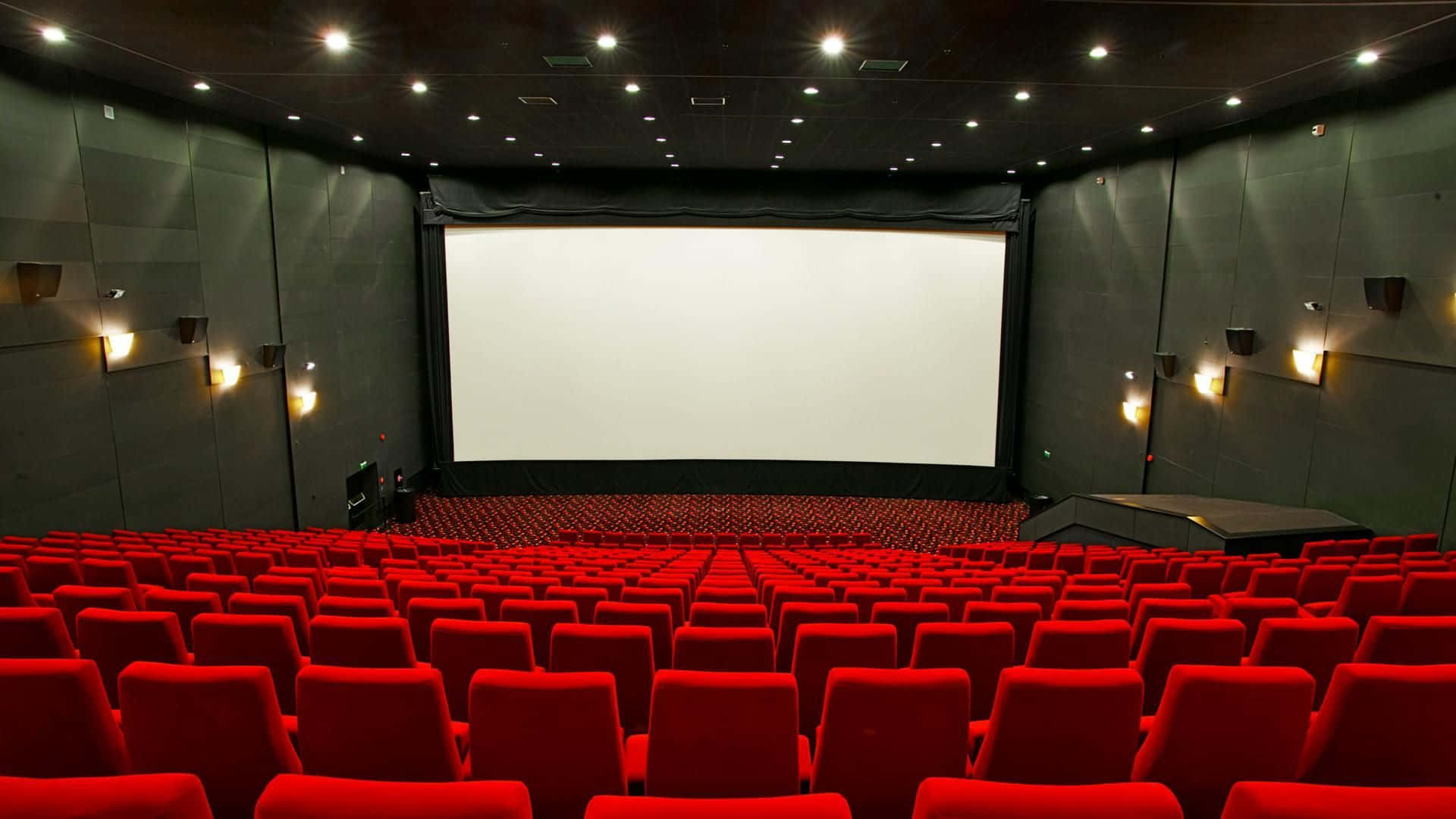 A Large Cinema With Red Seats And A Screen Wallpaper