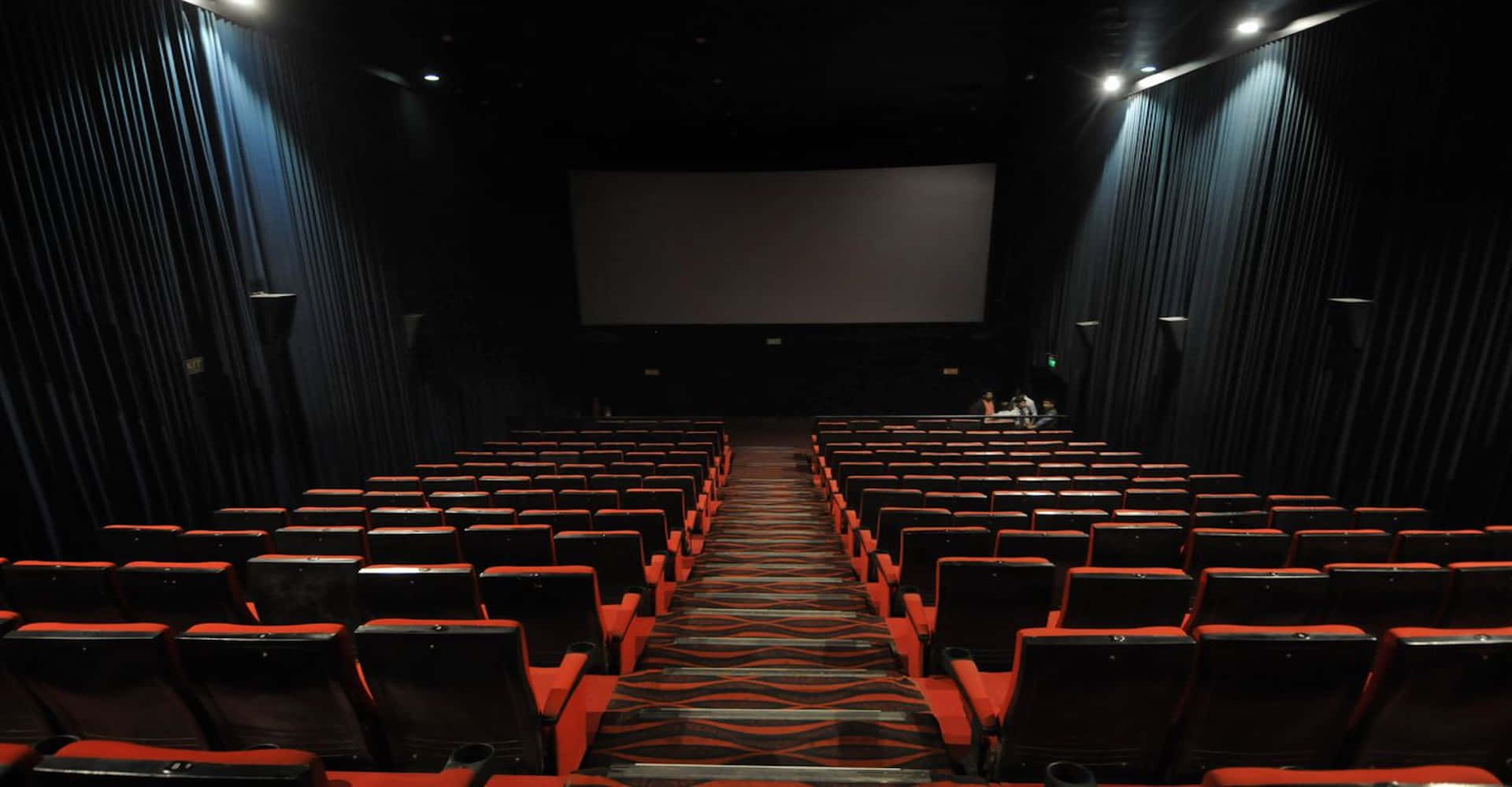 A Theater With Rows Of Seats And A Screen Wallpaper