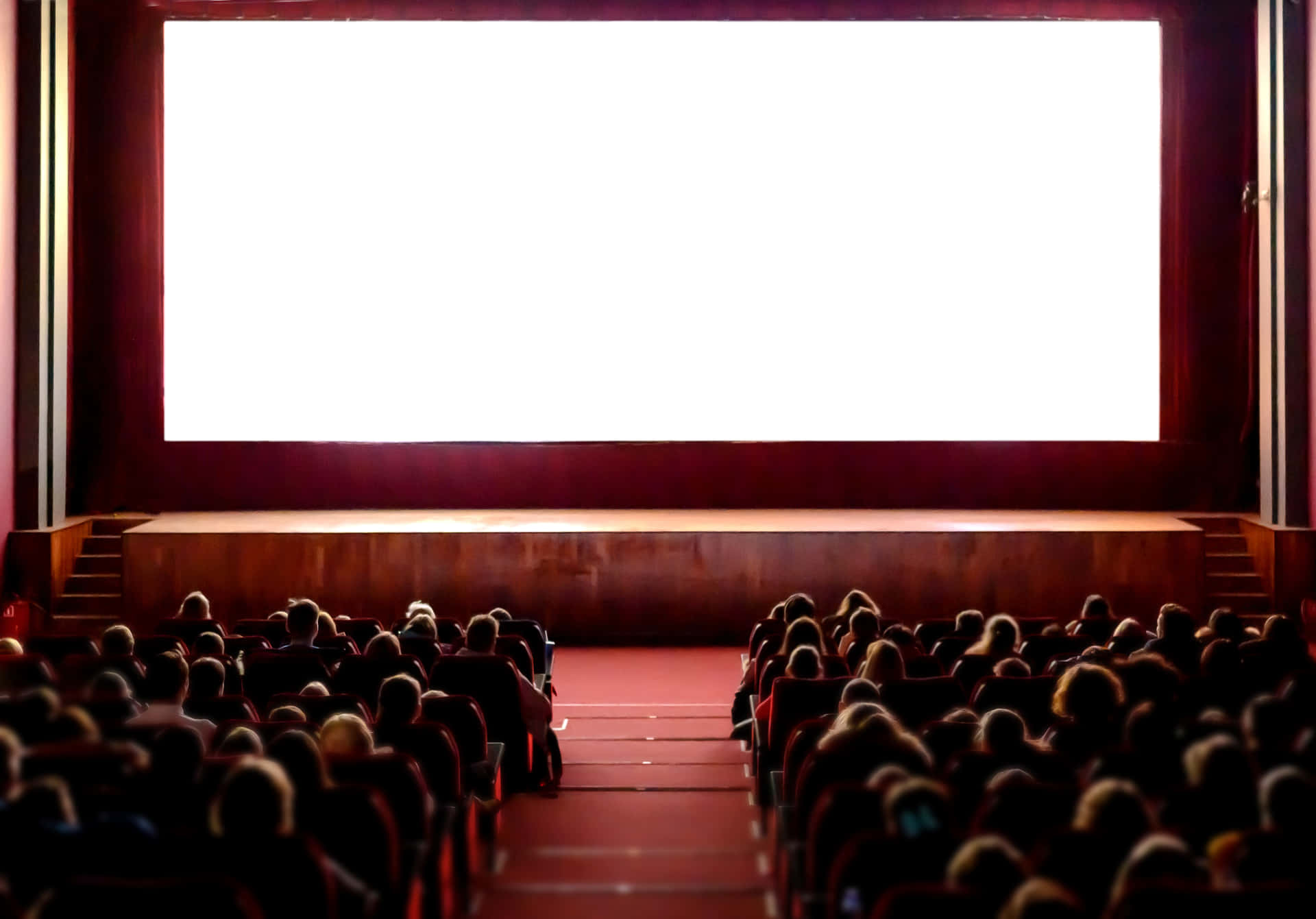 A Large Screen In A Theater With People Watching Wallpaper