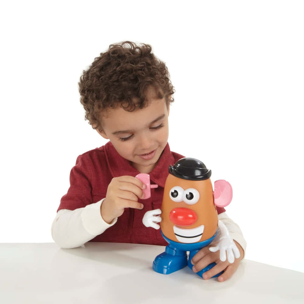 A Young Boy Is Playing With A Mr Potato Head