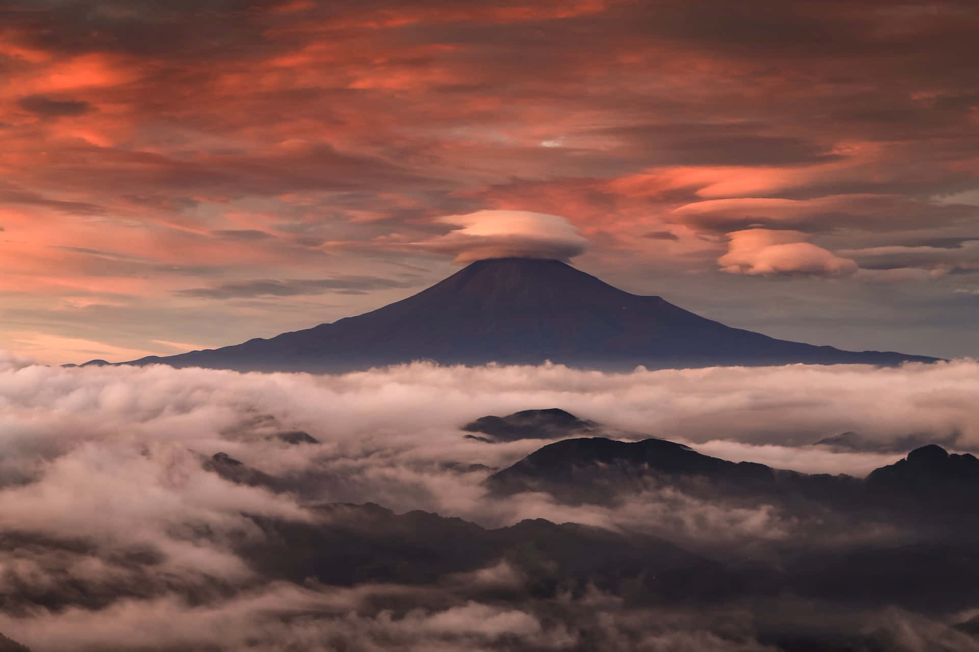 A Mountain Is Seen Above Clouds At Sunset