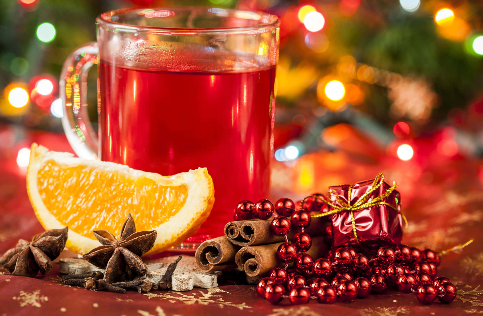 A steaming mug of mulled wine with cinnamon and orange garnish Wallpaper
