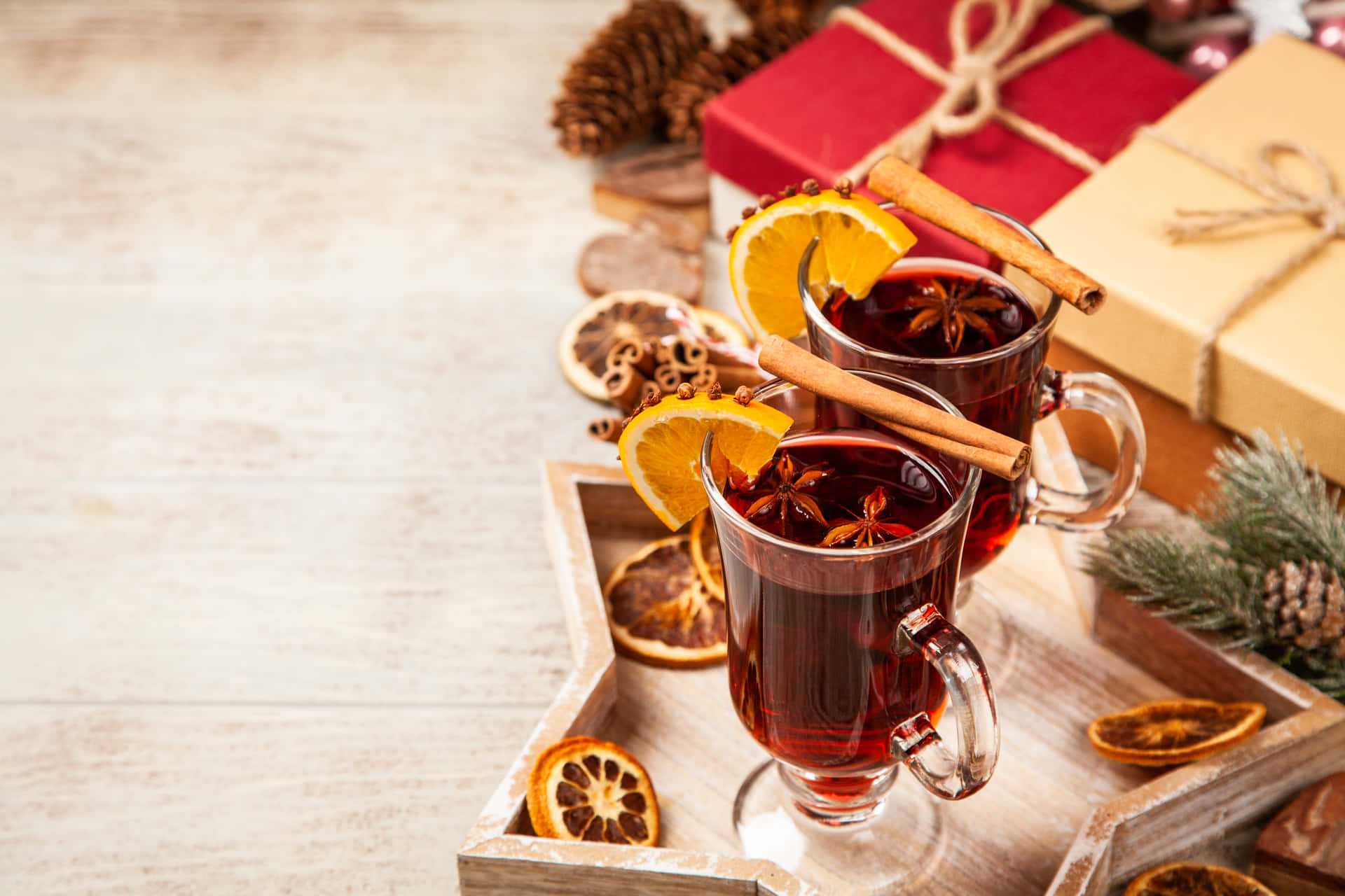 A steaming mug of mulled wine with cinnamon sticks and orange slices Wallpaper