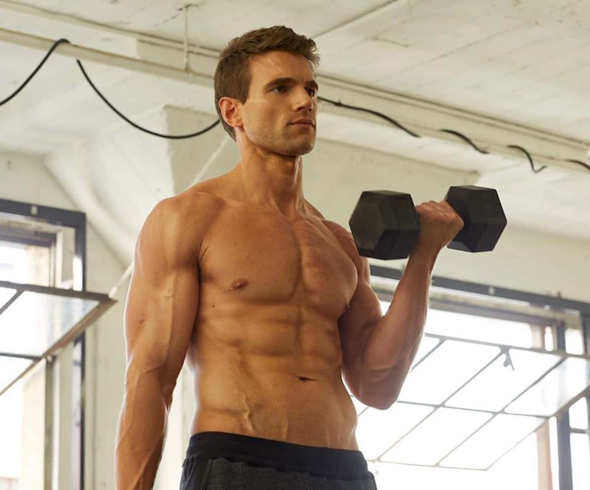Muscular Man Dumbbell Workout Gym Setting Wallpaper
