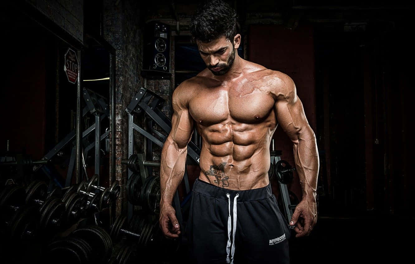 Muscular Man In Gym Showcasing Physique Wallpaper