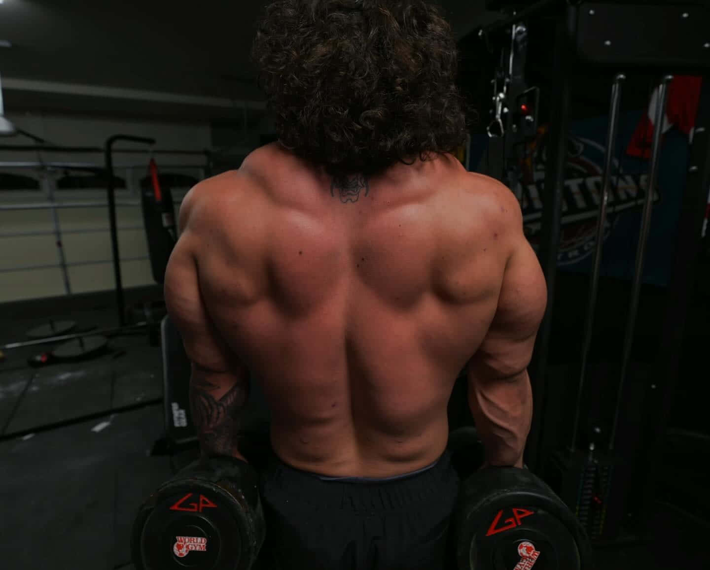 Muscular Man Performing Dumbbell Workout Gym Wallpaper
