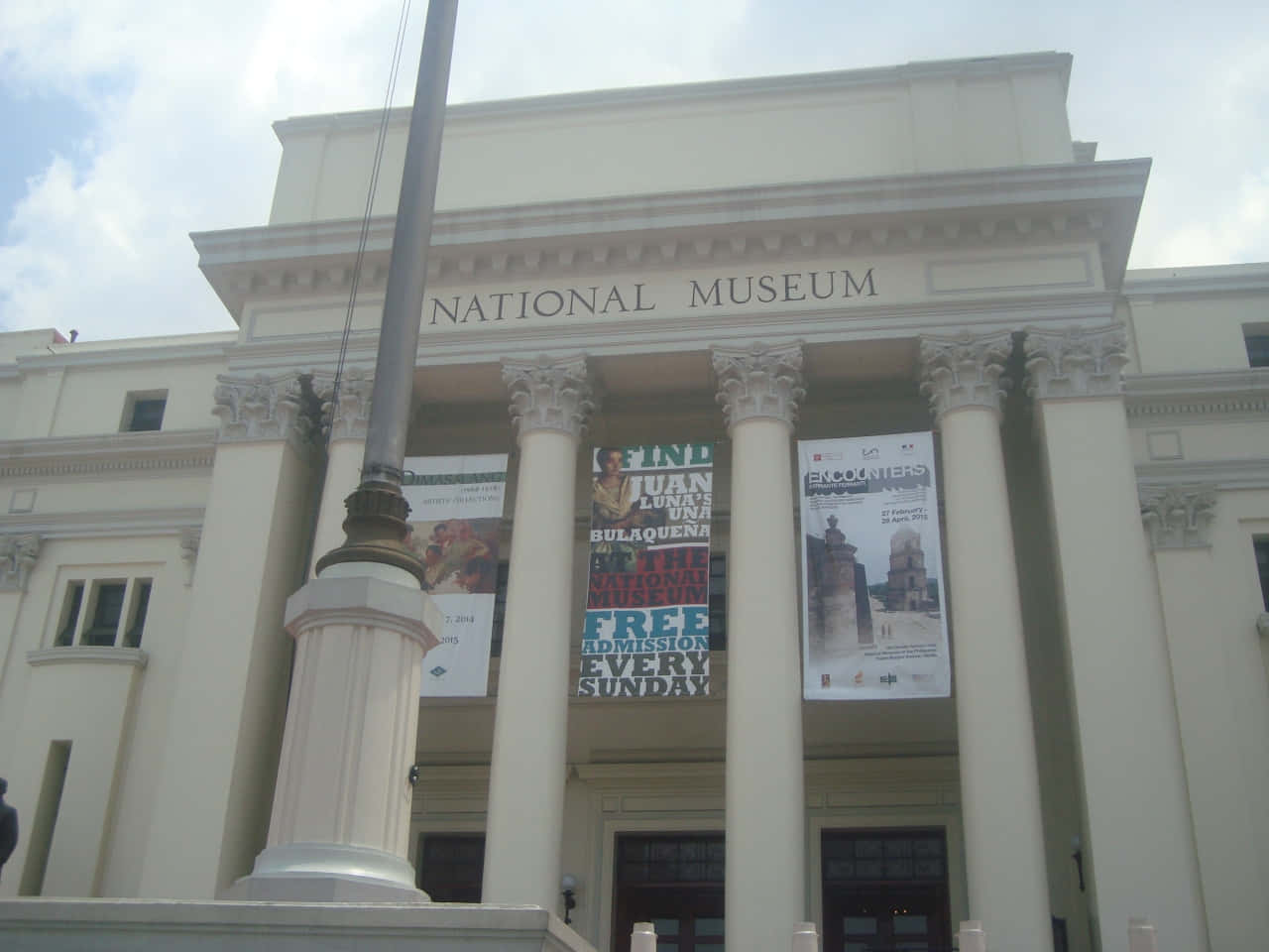 A Large Building With Columns And A Flag