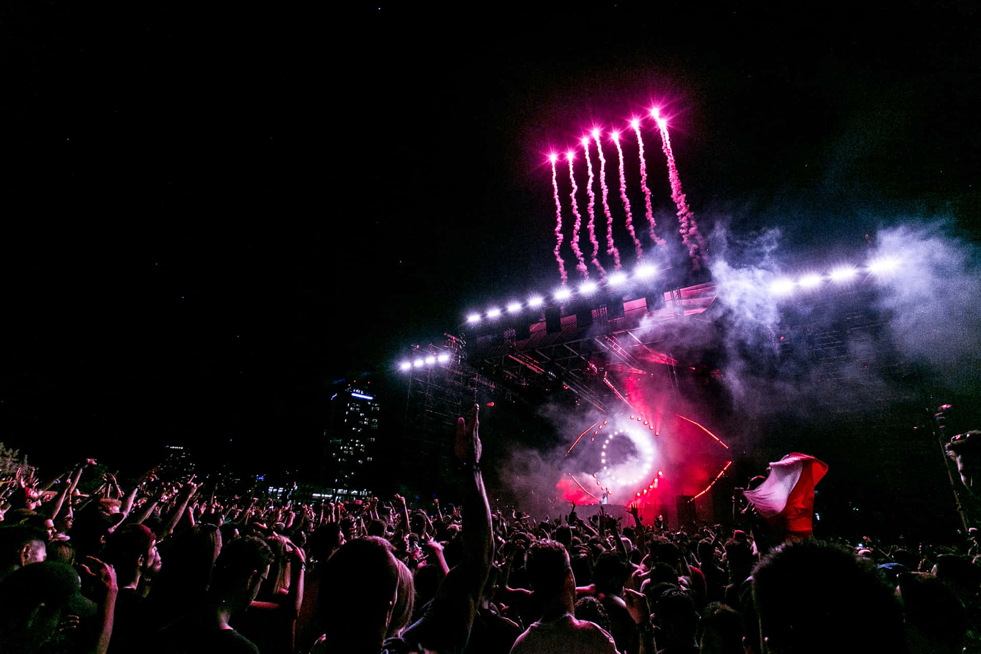 Energized music festival crowd under a vibrant sunset skyline Wallpaper