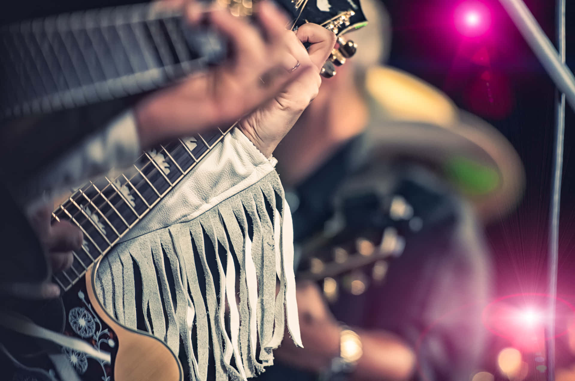 Billede af person med guitar, der spiller musik i abstrakte farver.