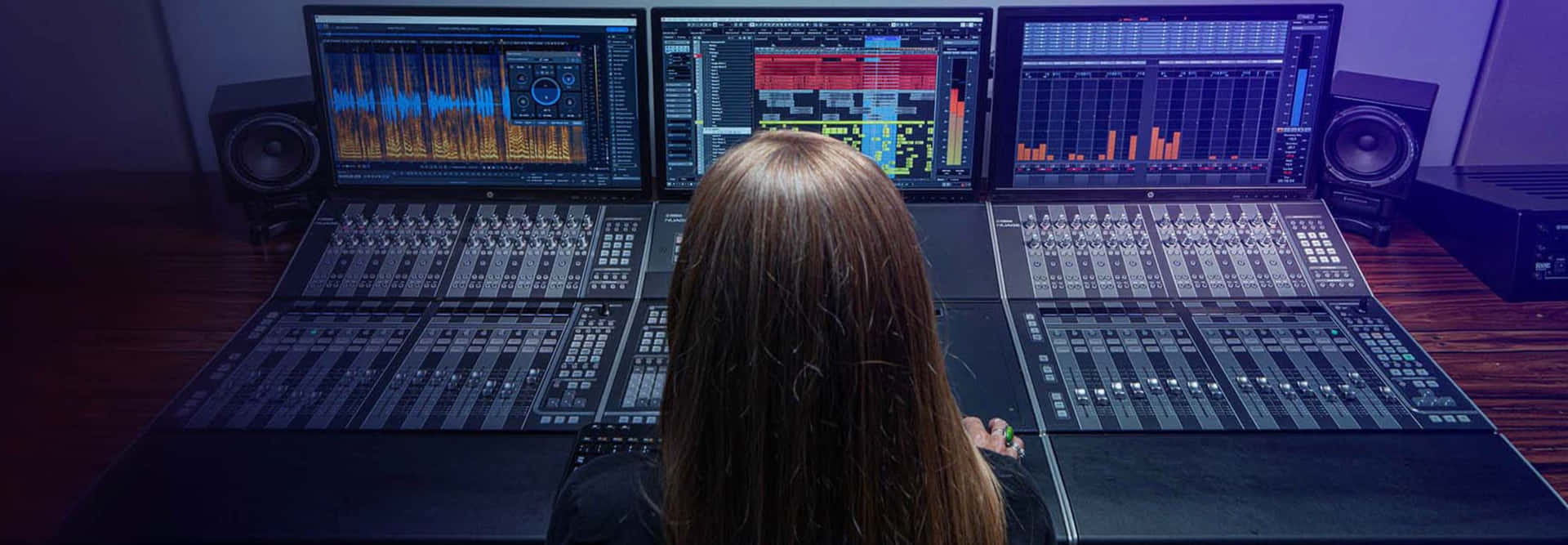 A Woman Is Sitting In Front Of Several Monitors In A Recording Studio