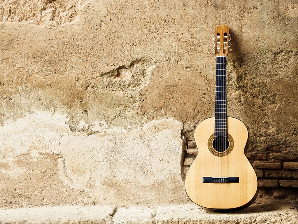 Imagende Una Guitarra De Instrumento Musical Apoyada Contra Una Pared.