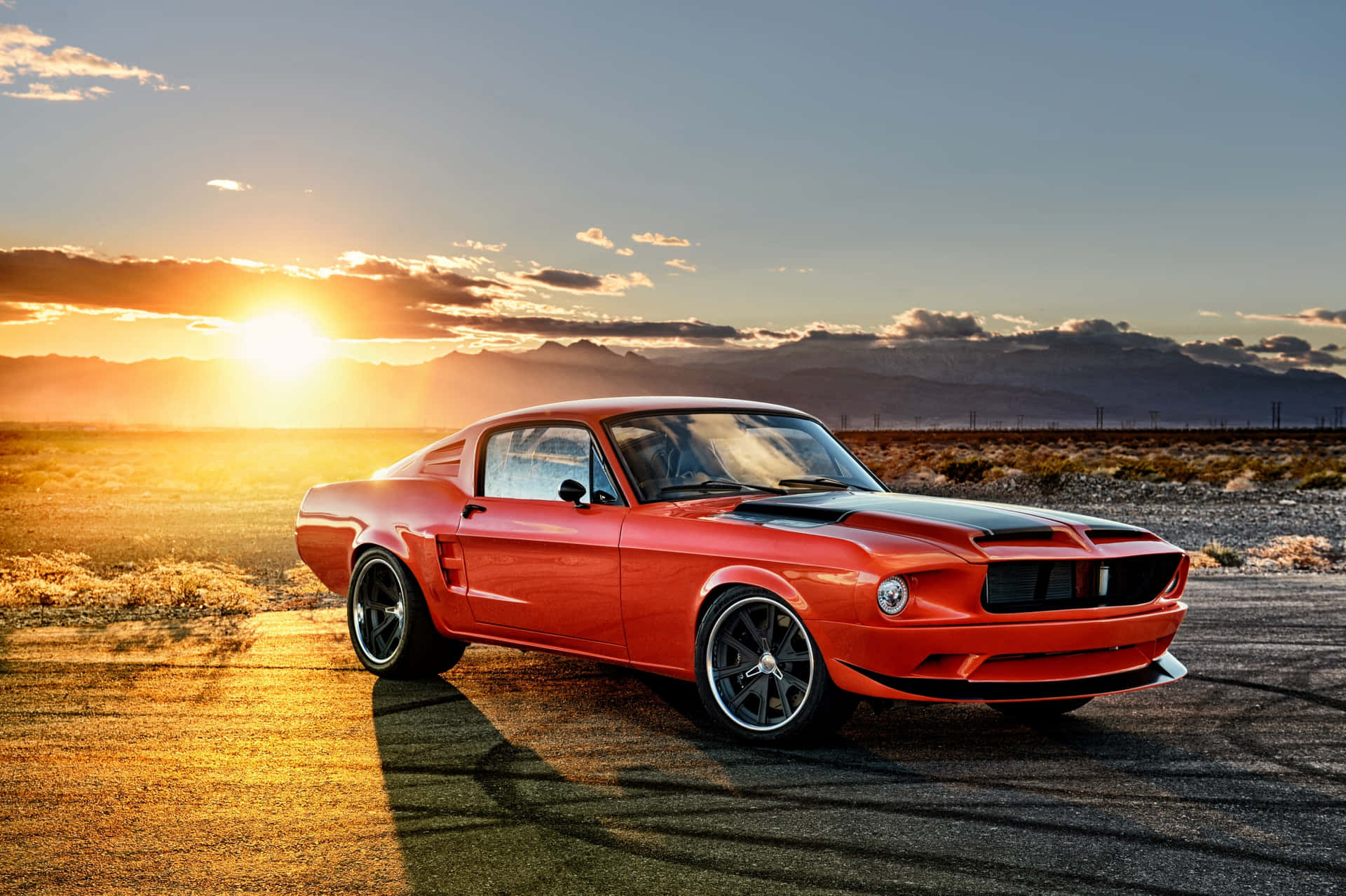 En rød Mustang parkeret i ørkenen ved solnedgang