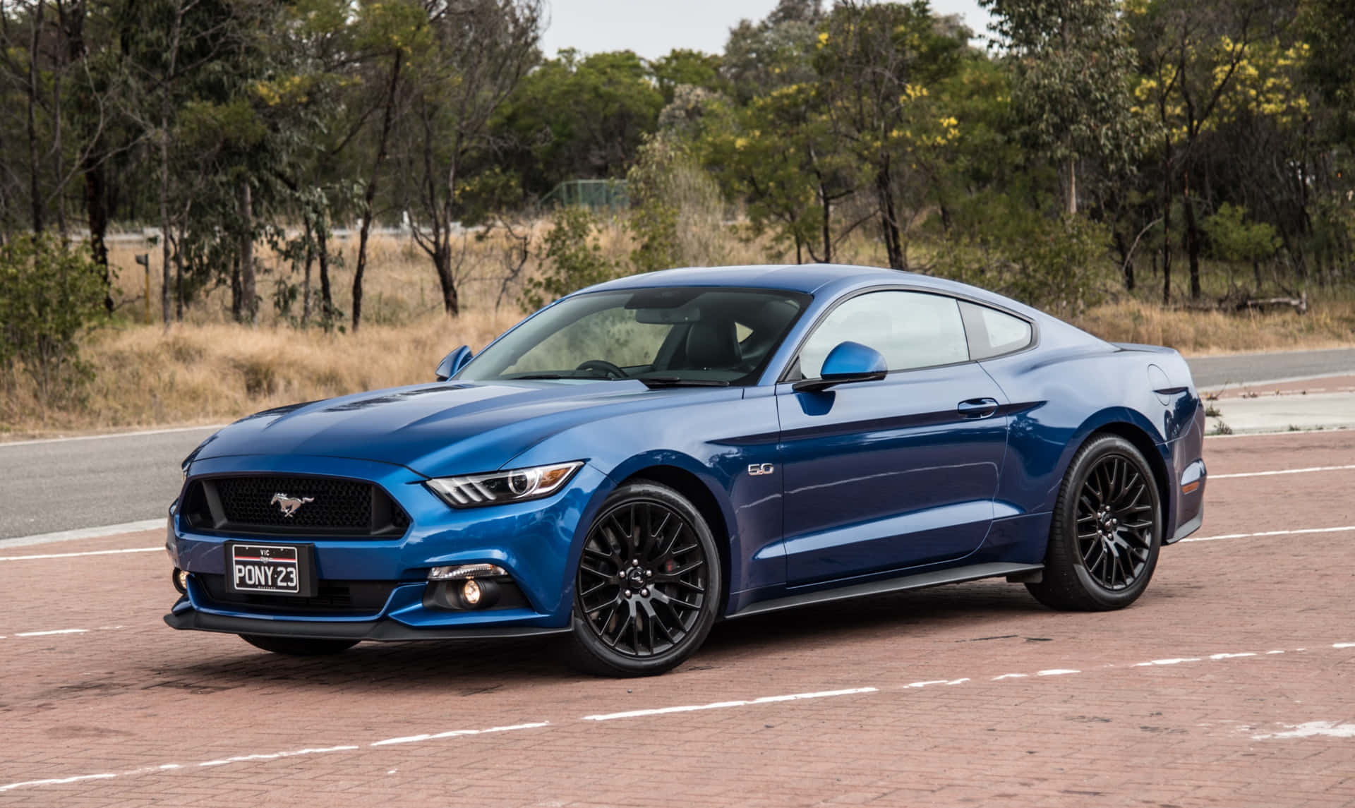 The Blue Ford Mustang Is Driving Down The Road