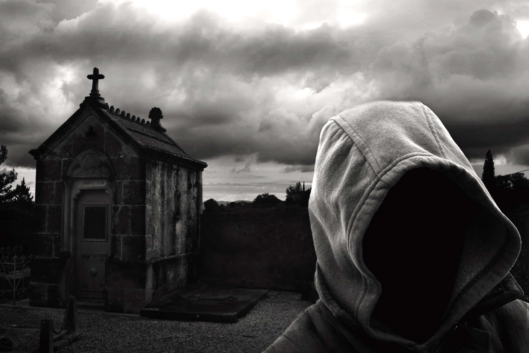 A Person In A Hoodie Standing In Front Of A Cemetery