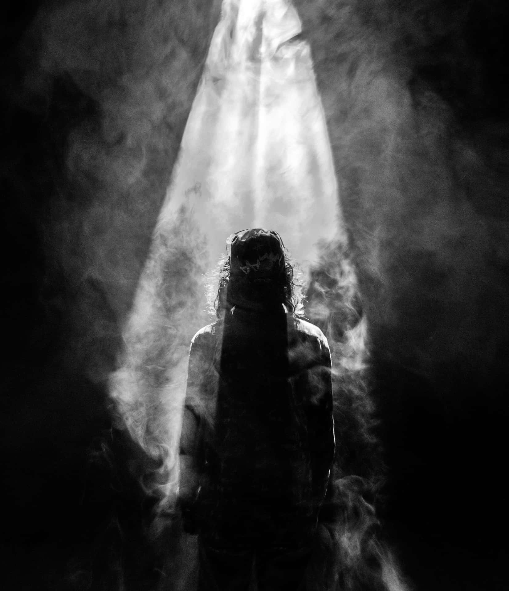 A Black And White Photo Of A Person Standing In The Smoke