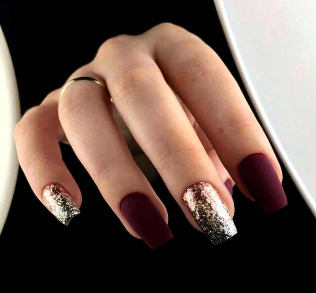 A Woman's Hand With Burgundy And Silver Nails