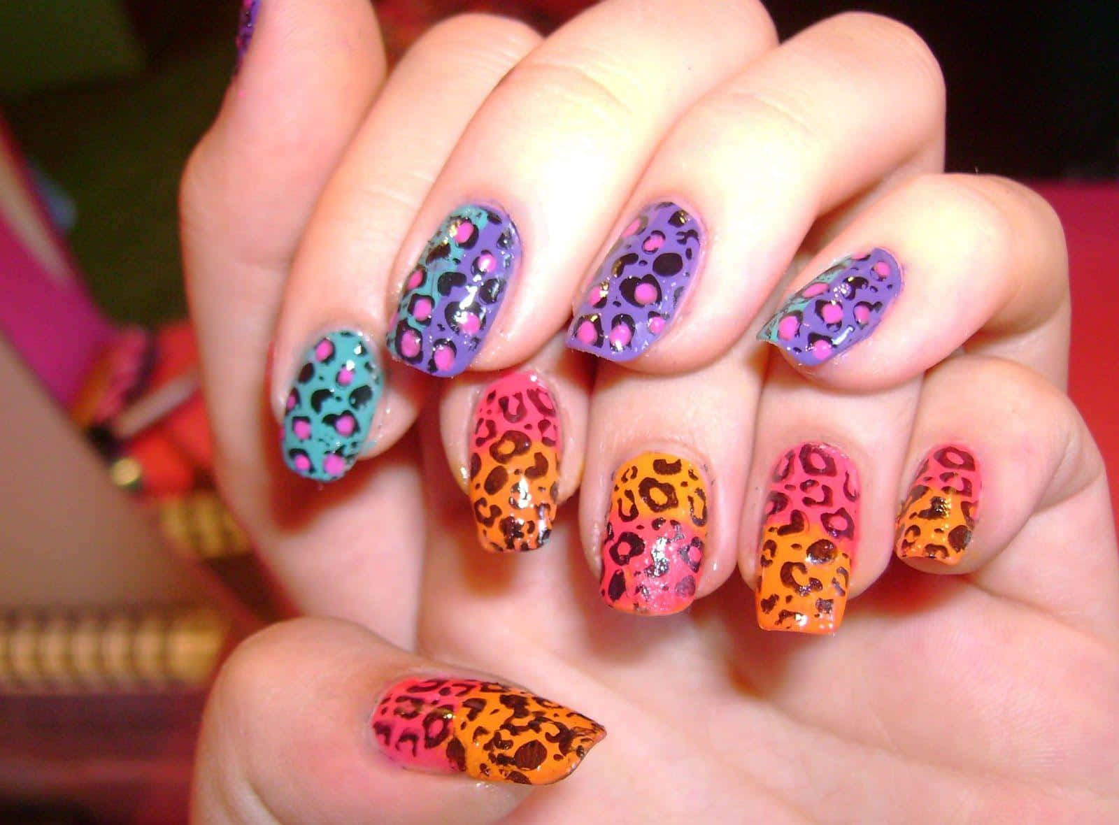 A Woman Holding Up A Pair Of Colorful Leopard Print Nails