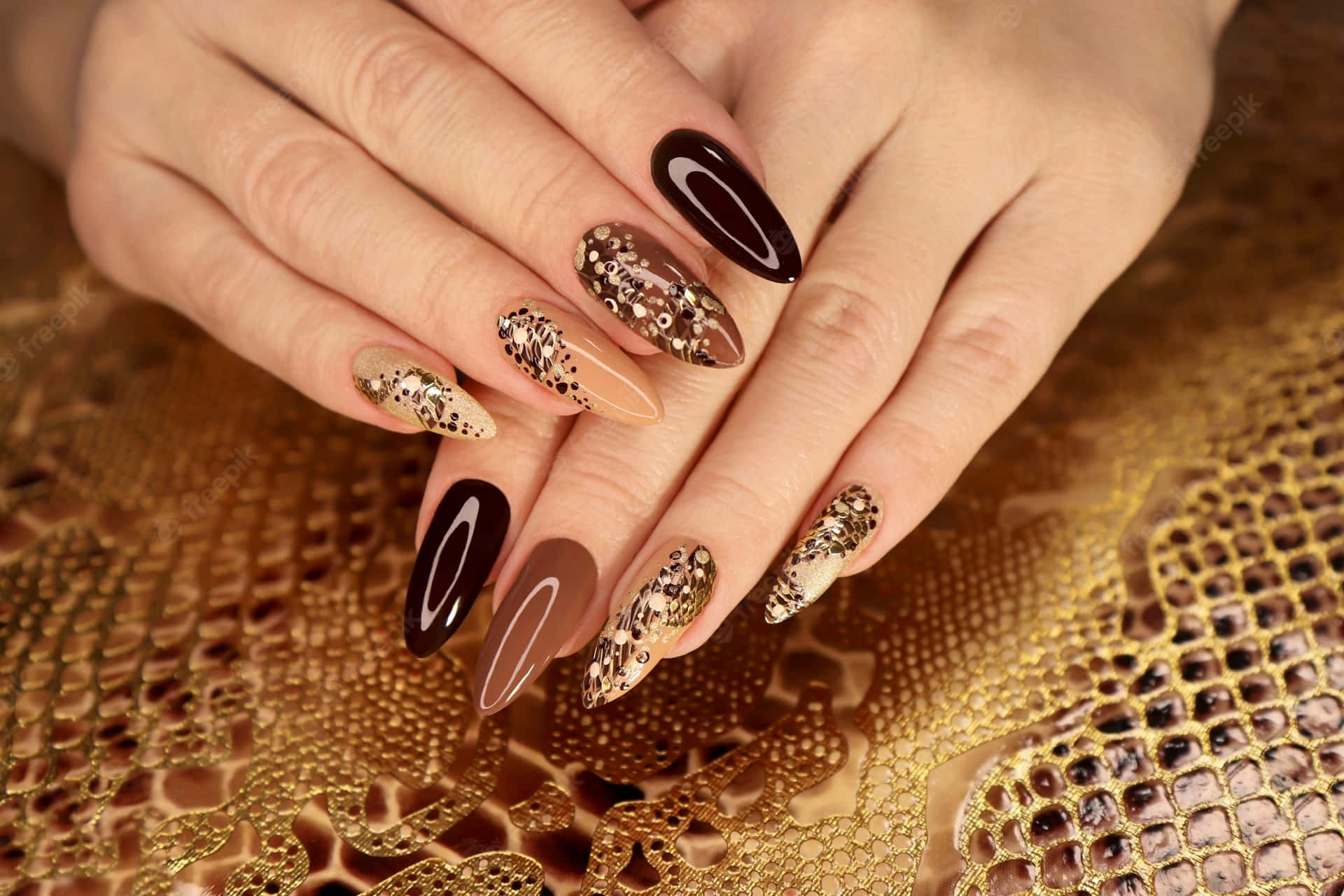 A Woman's Hands With Brown And Gold Nails