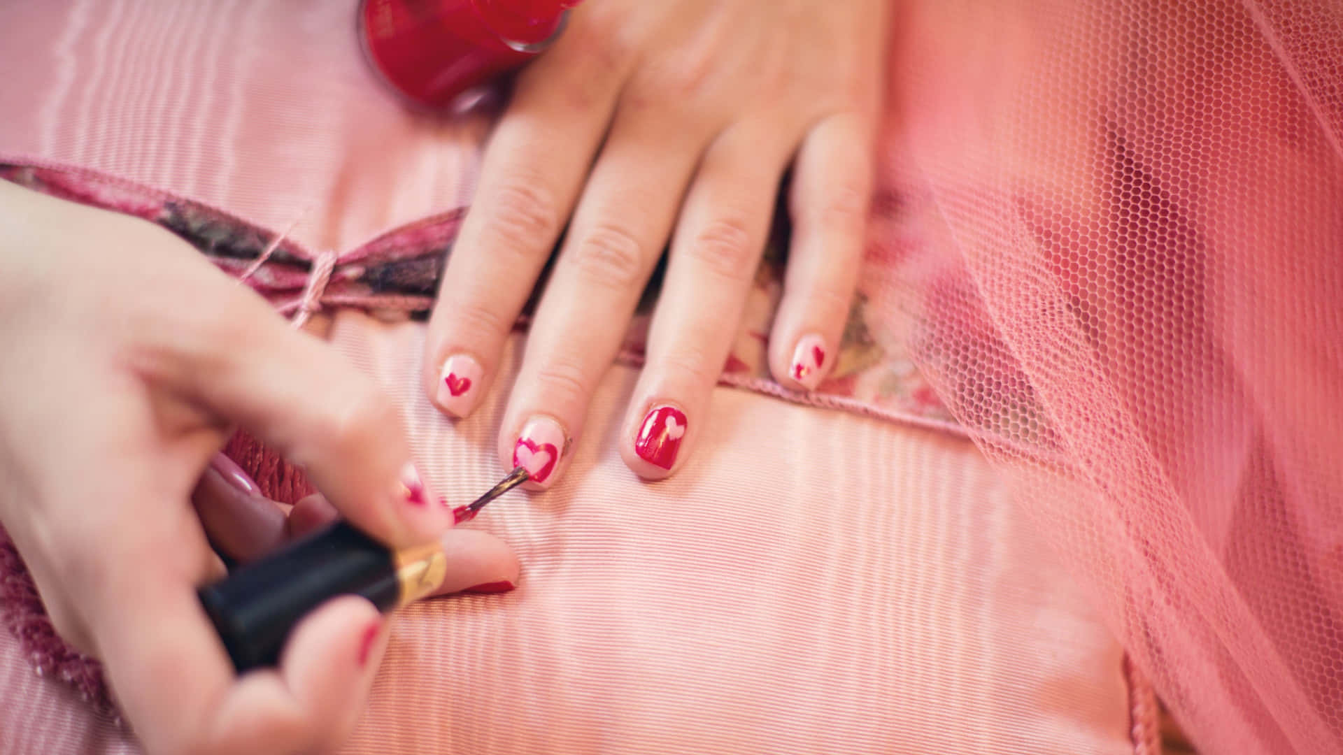 A Woman Is Painting Her Nails With A Pink Nail Polish