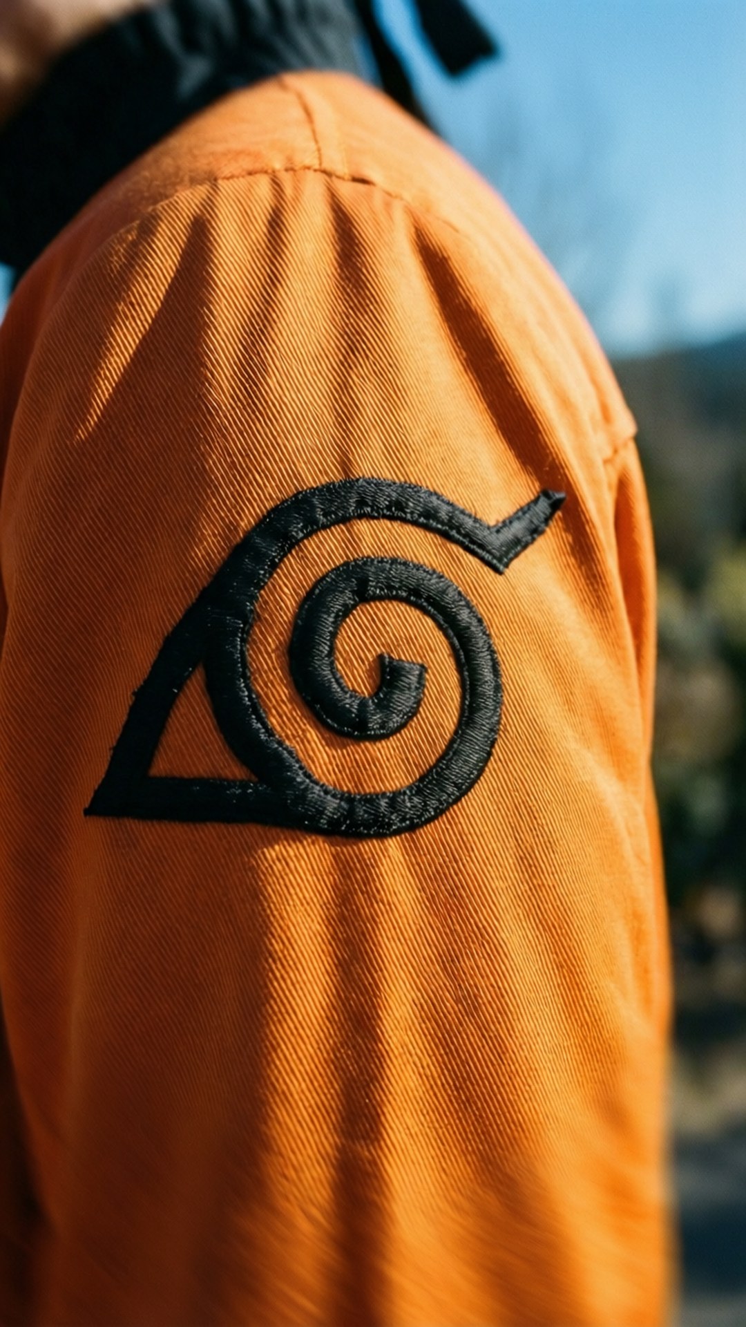Nærbilde av Hidden Leaf-symbolet på Narutos oransje jakke.