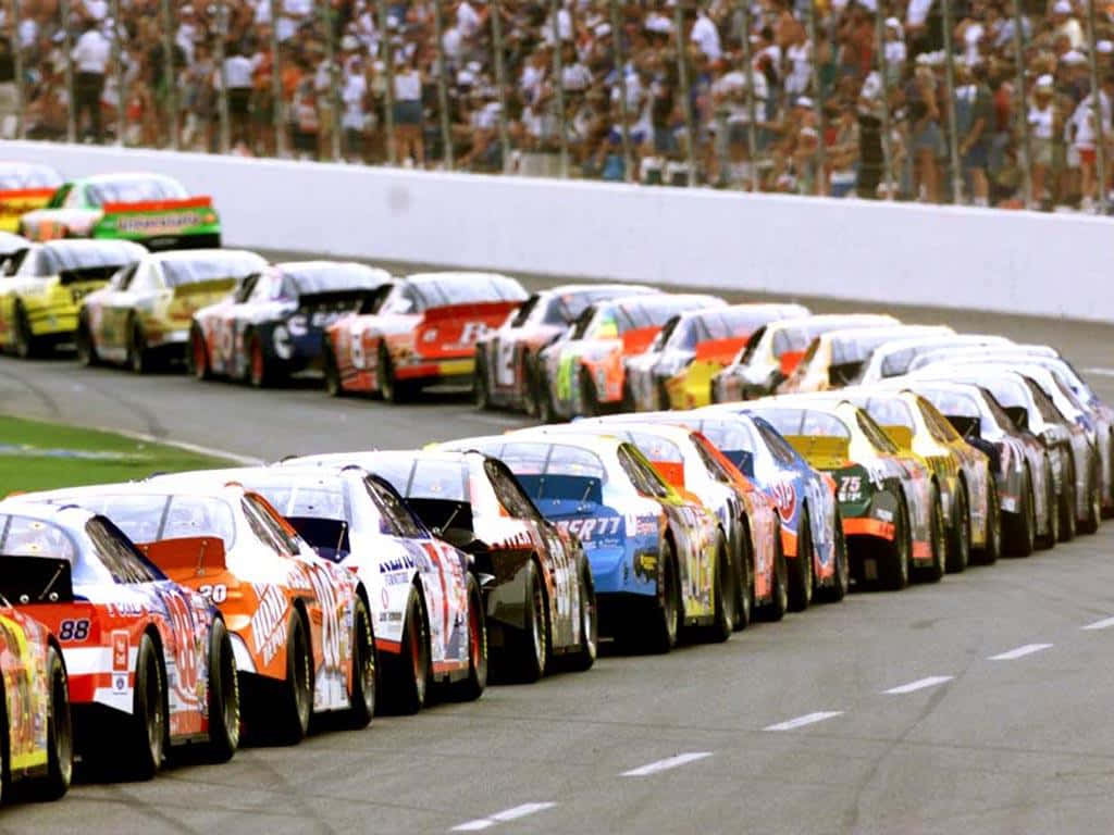 En racebil brøler rundt om en bane under en NASCAR race. Wallpaper