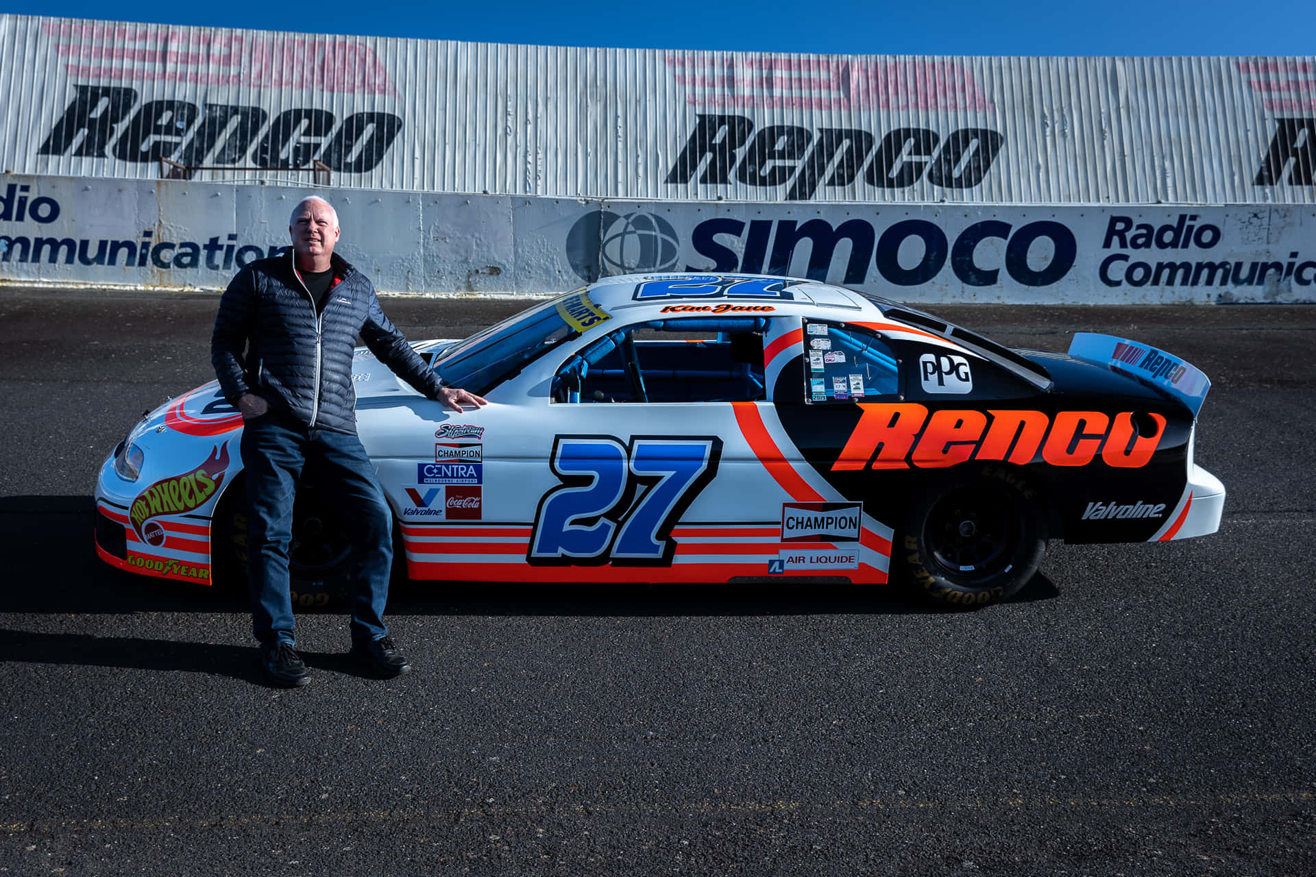 A Man Standing Next To A Race Car