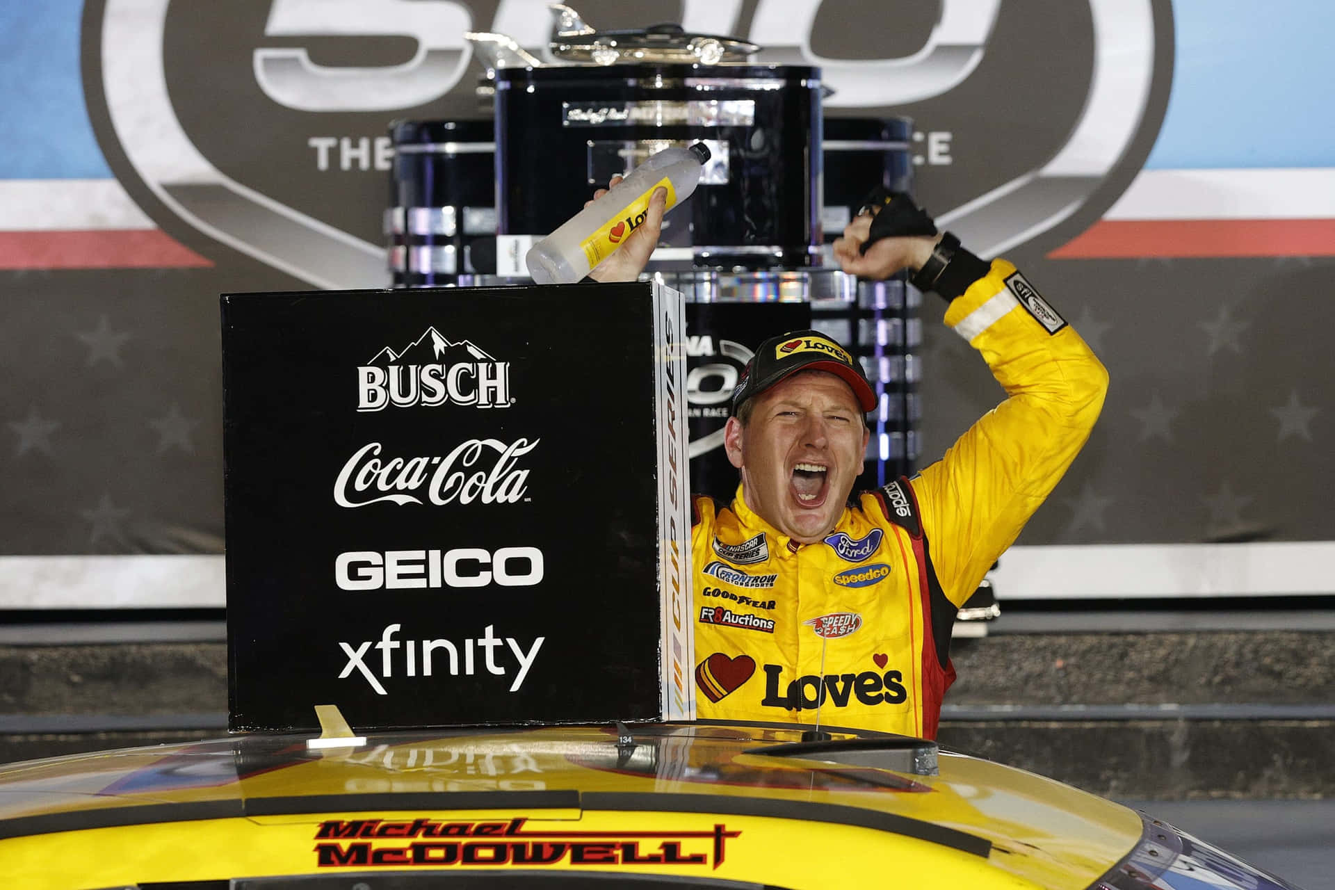 A Nascar Driver Is Holding Up His Trophy