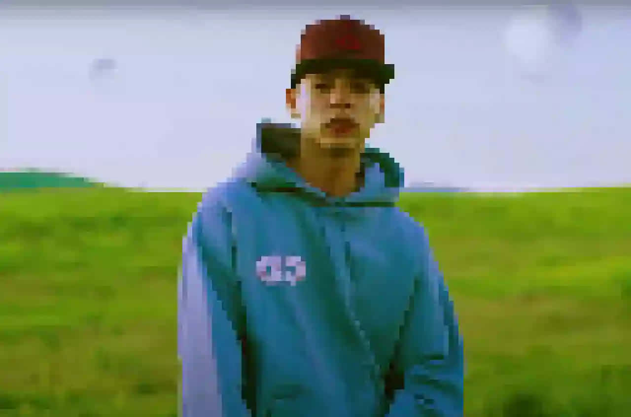 A Man In A Blue Hoodie Standing In A Field Wallpaper