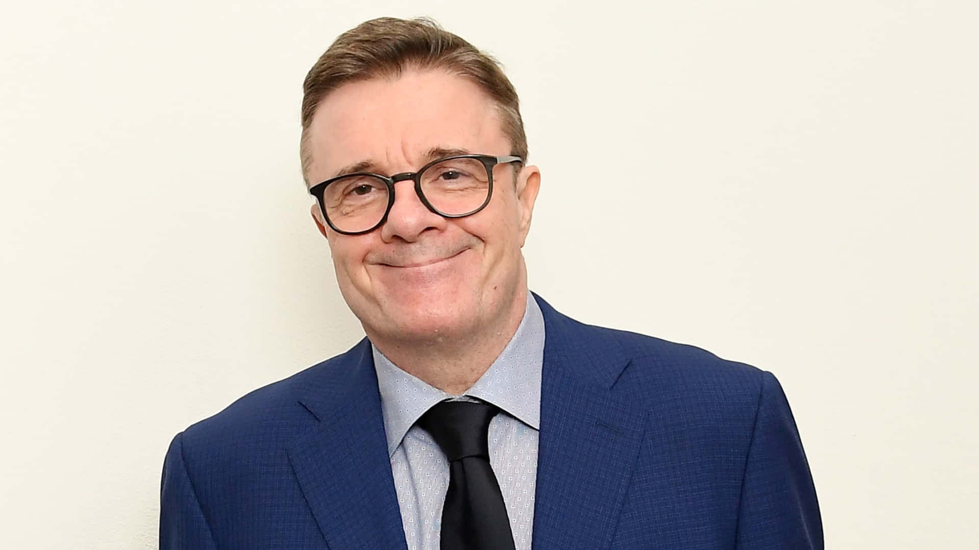 Actor Nathan Lane wearing a suit and red tie Wallpaper