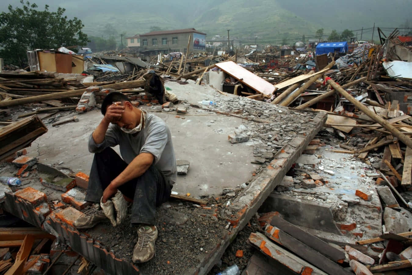 A Man Sits On The Ground In Front Of Rubble