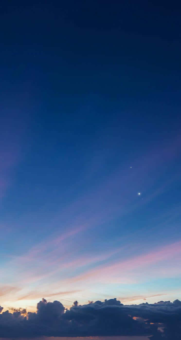 En solnedgang med en blå himmel og en lyserød sky Wallpaper