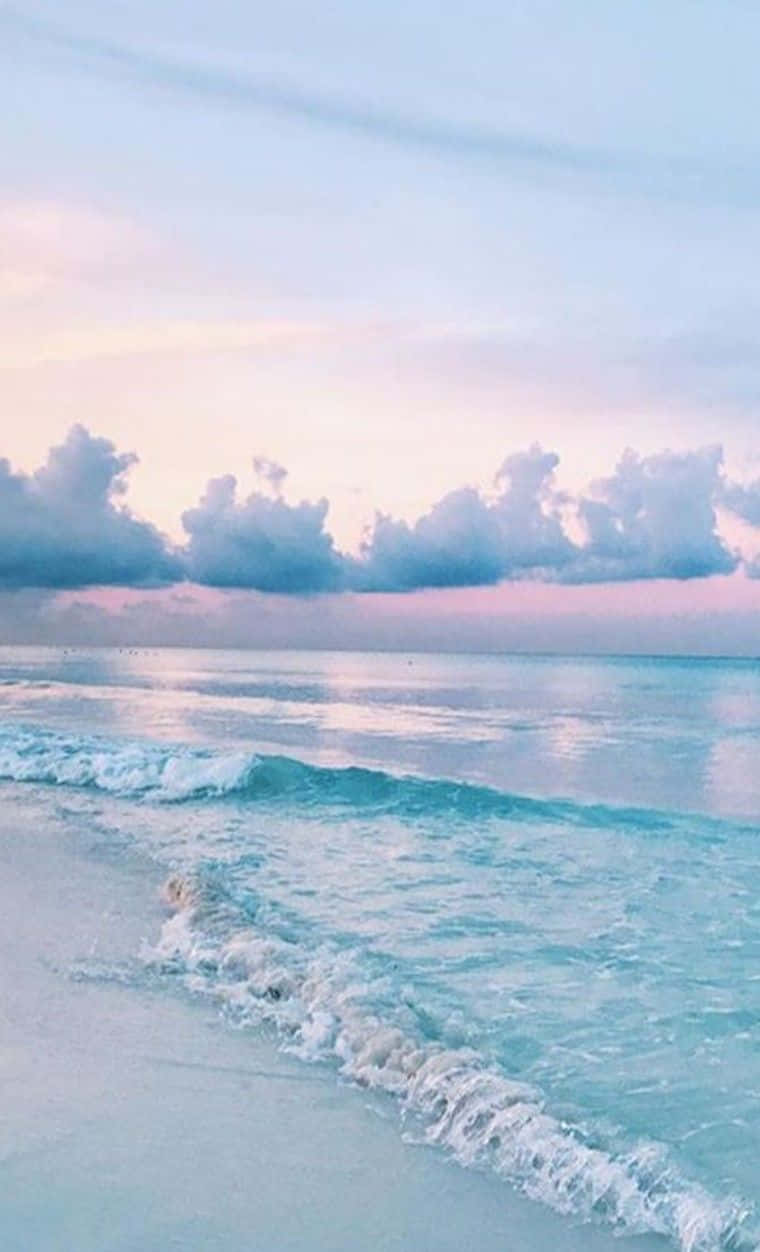 A Beach With Waves And Clouds At Sunset Wallpaper