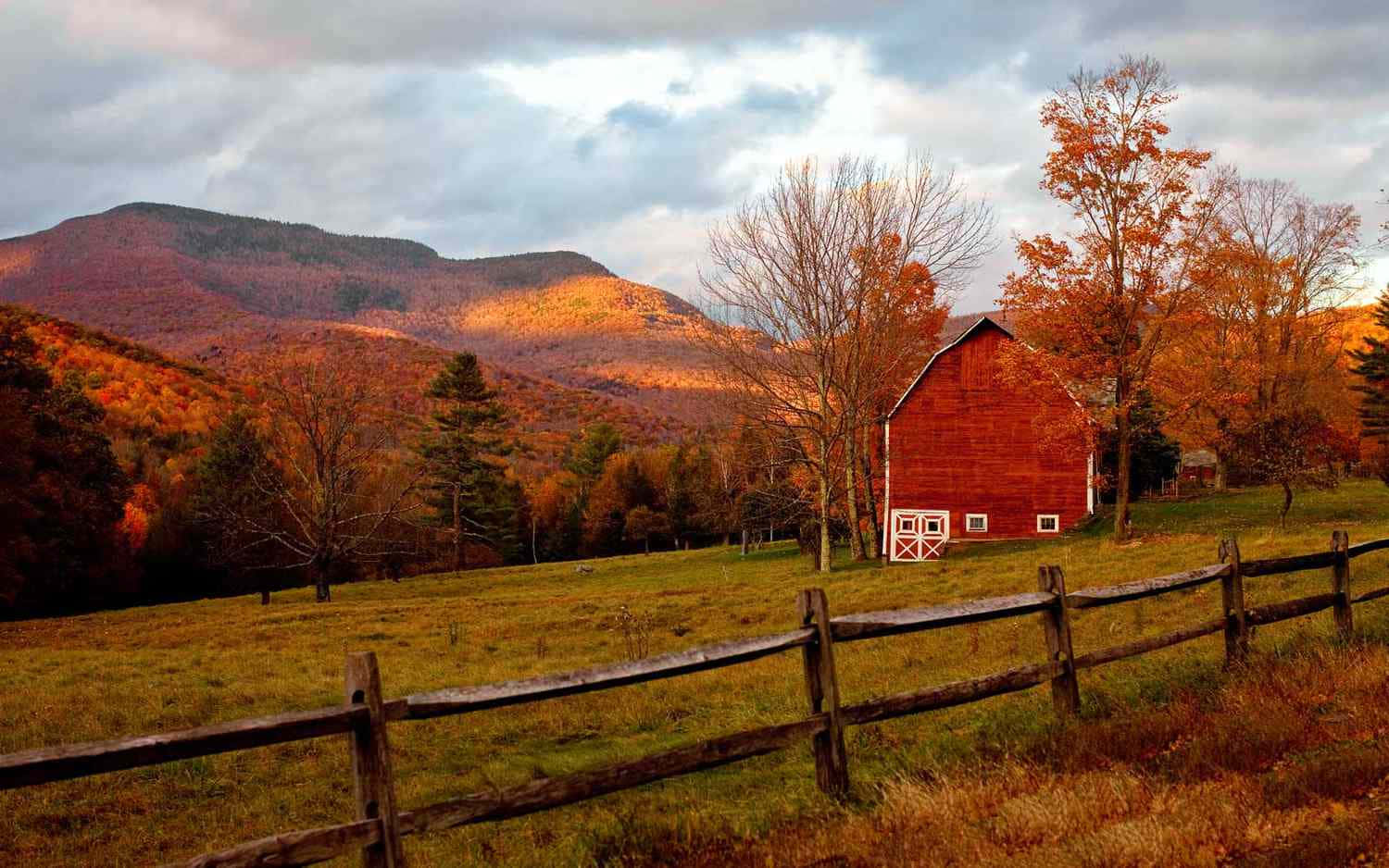 A Red Barn In The Fall With Mountains In The Background