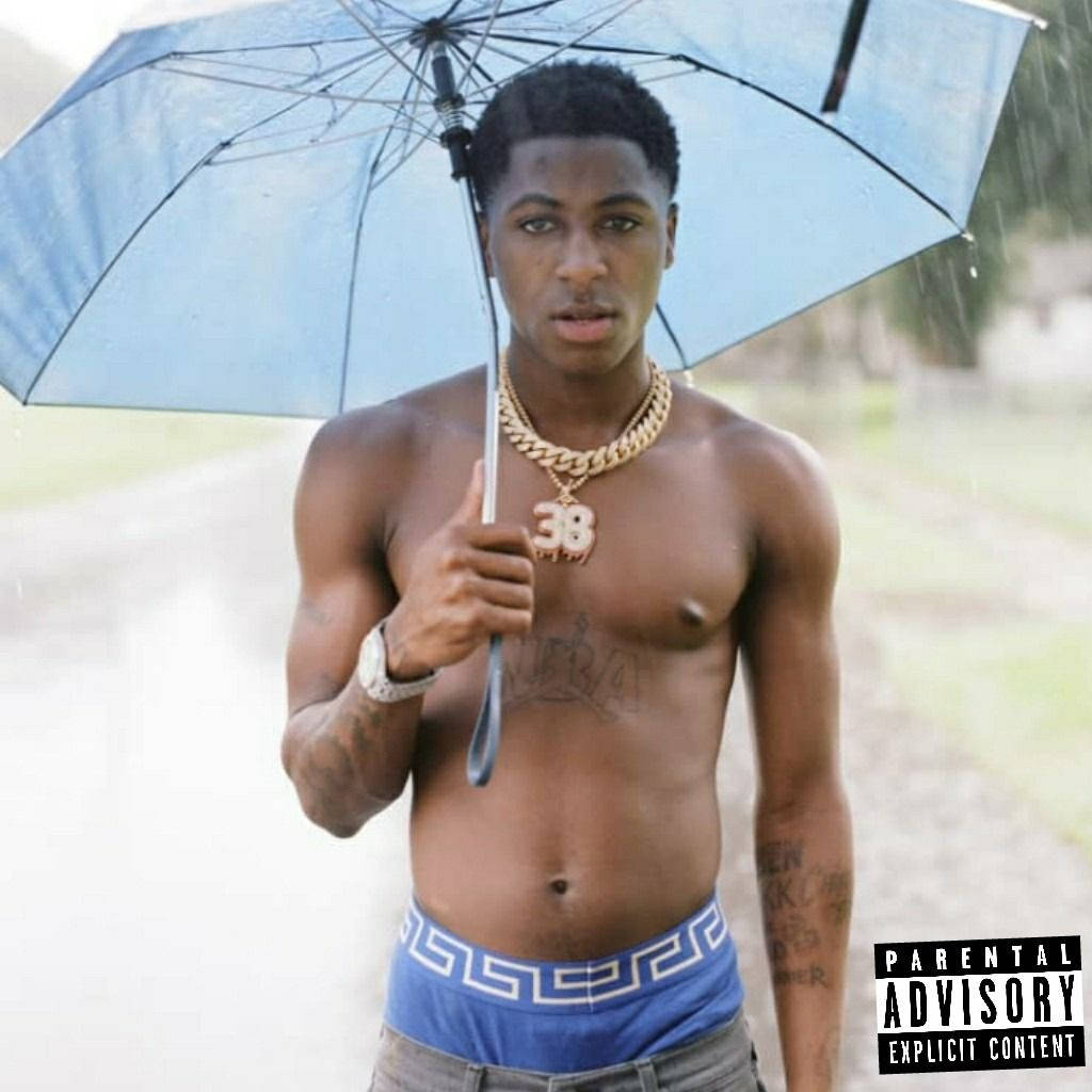NBA Youngboy ducks under a blue umbrella in style Wallpaper