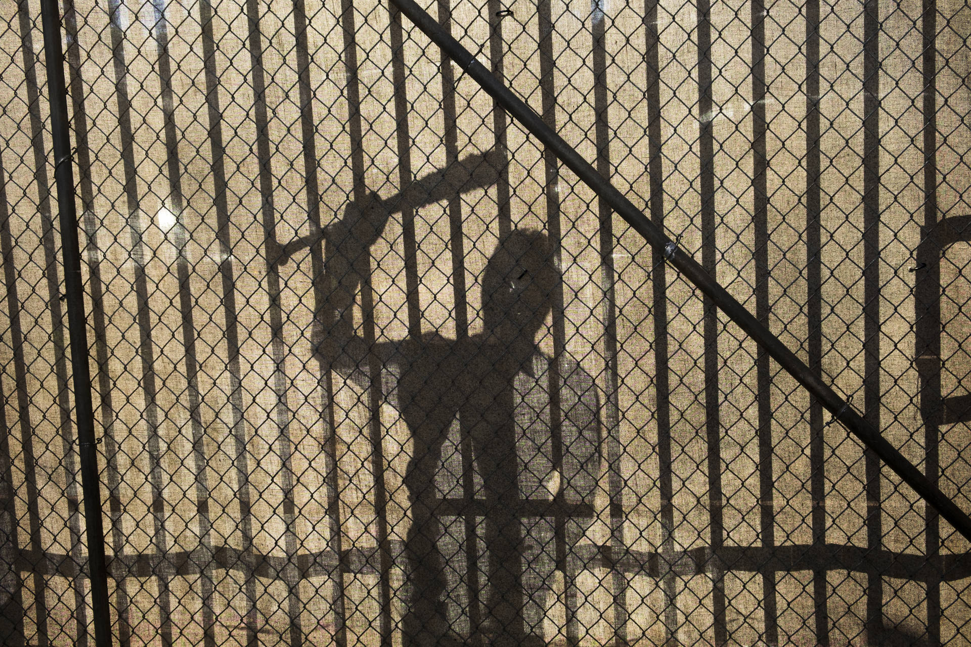 Negan's Shadow Against A Fence Wallpaper