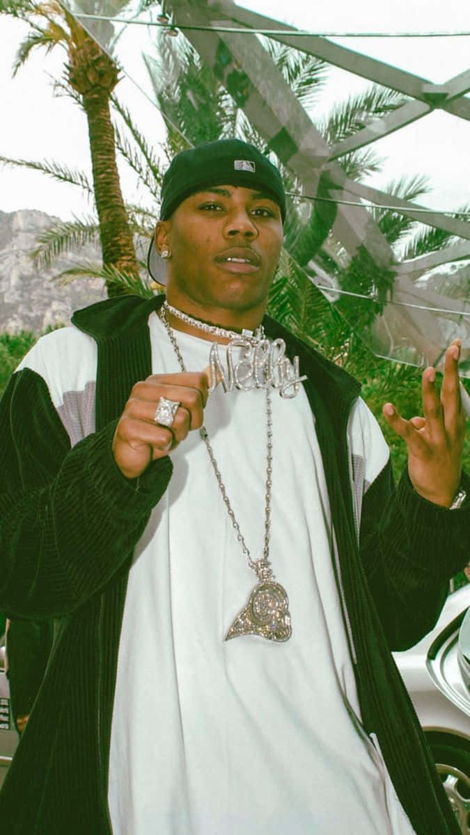 Nelly Proudly Holding Silver Pendant With His Name Wallpaper