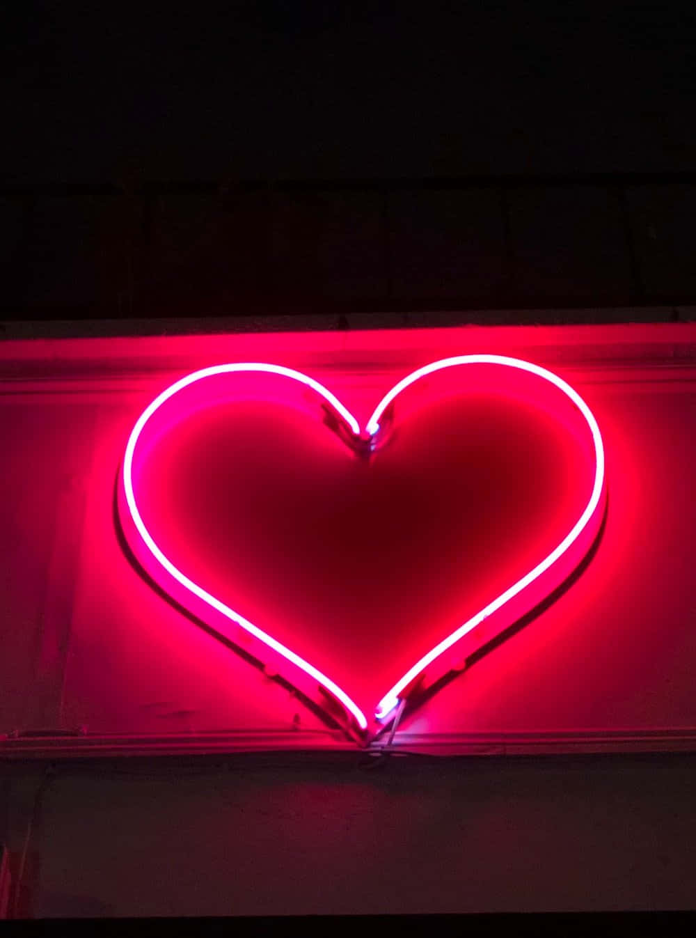 Iluminaciónde Corazón Neón Rosa Intenso En Un Ángulo Bajo Fondo de pantalla