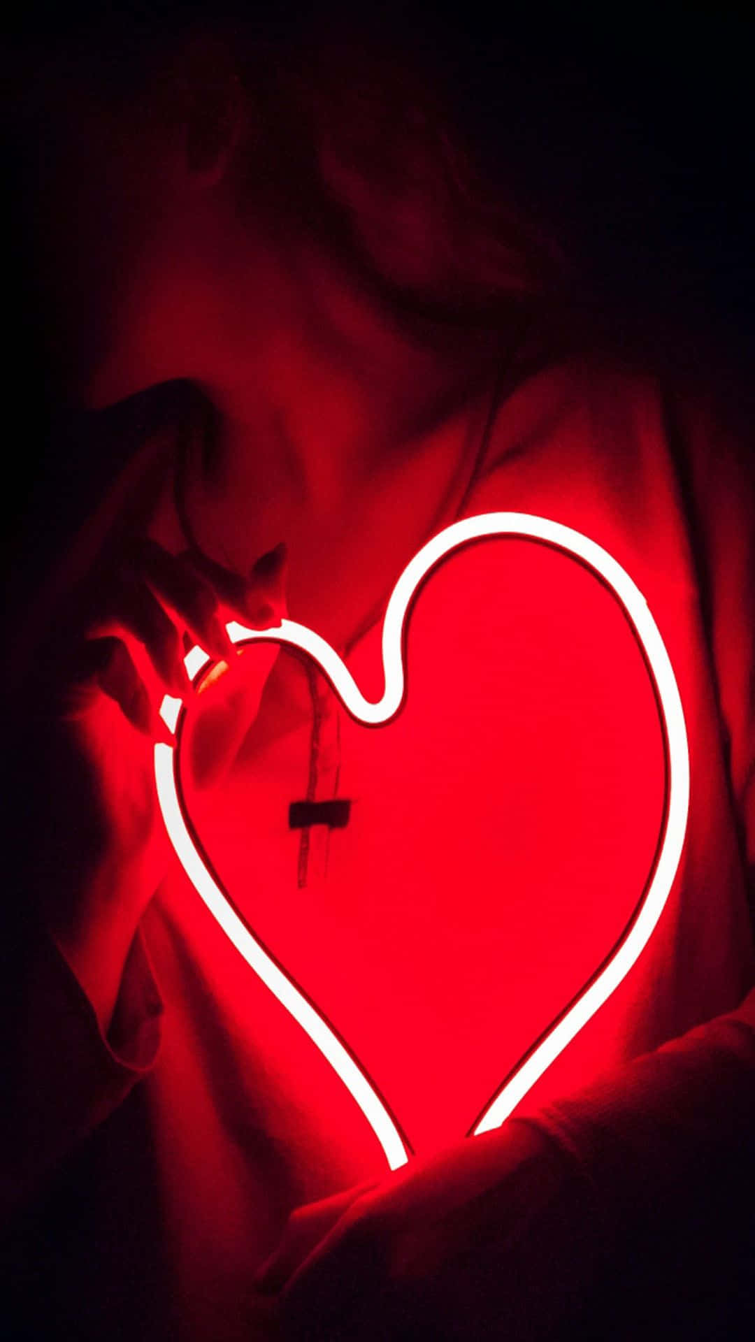 Unamujer Sosteniendo Un Letrero De Neón En Forma De Corazón Rojo Fondo de pantalla