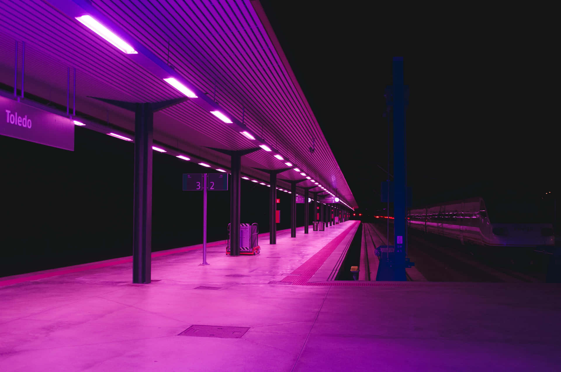 Neon Lit Train Stationat Night Wallpaper