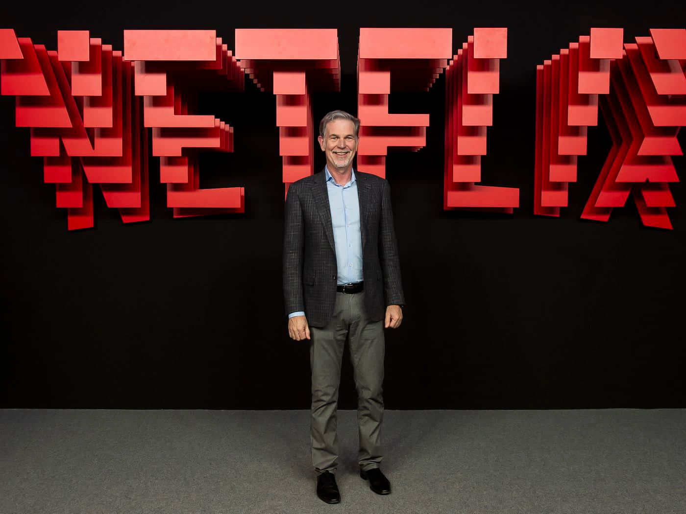 Netflix's John Savage Poses In Front Of The Netflix Logo
