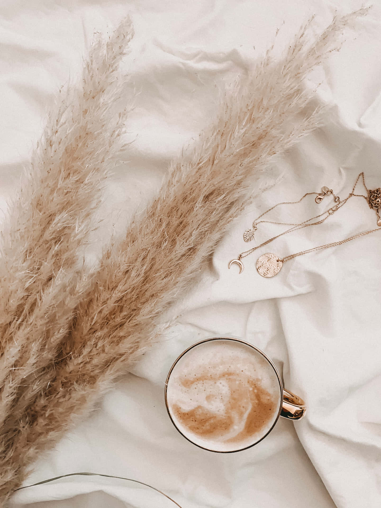 A Cup Of Coffee And A Necklace On A Bed