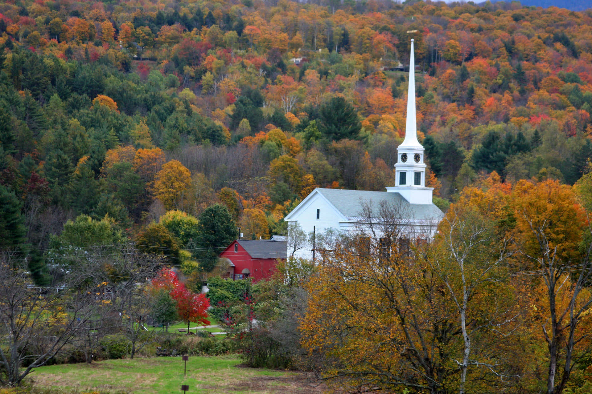 a white church surrounded by fall foliage Wallpaper