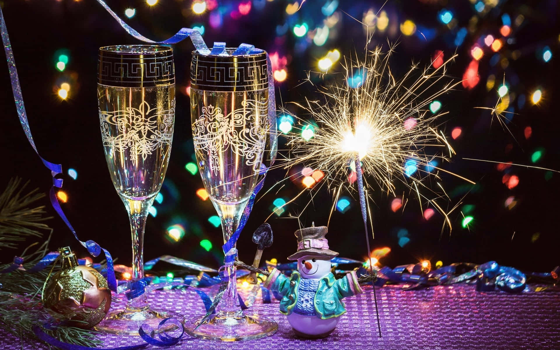 champagne glasses with fireworks and snowman on a table