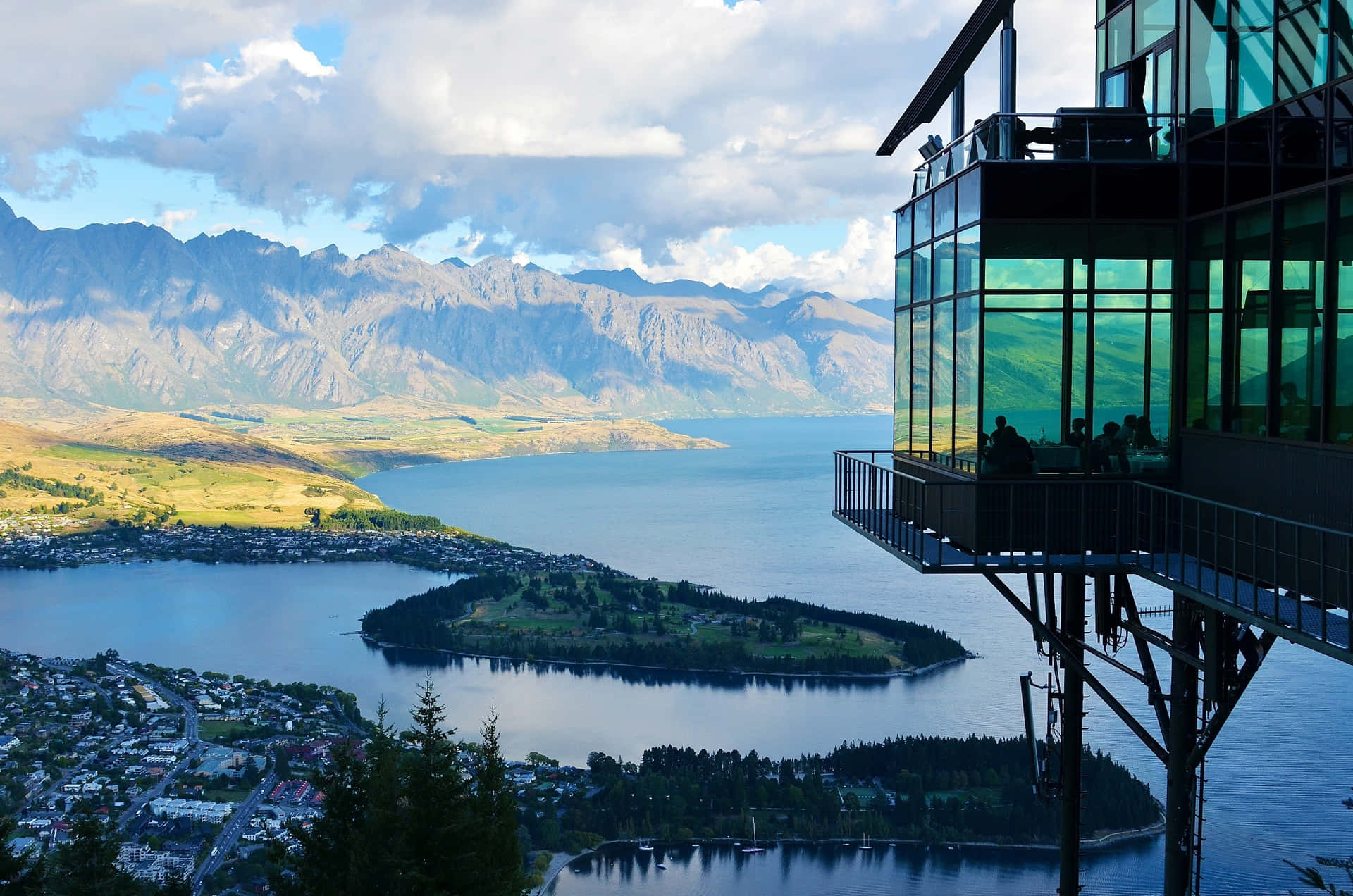 A View Of A Lake And Mountains From A Glass Building